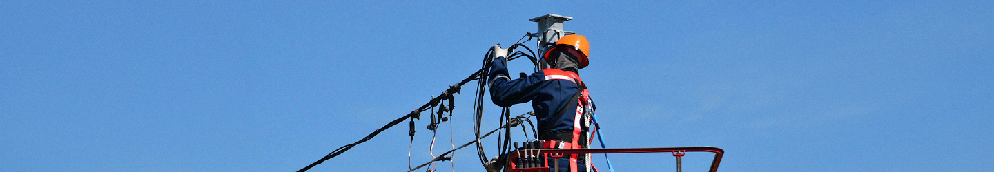 Eletricista a trabalhar num poste elétrico durante a instalação de cabos elétricos